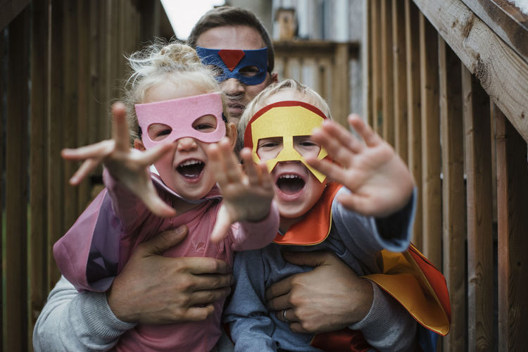 Portrait of children with father in superhero costumes