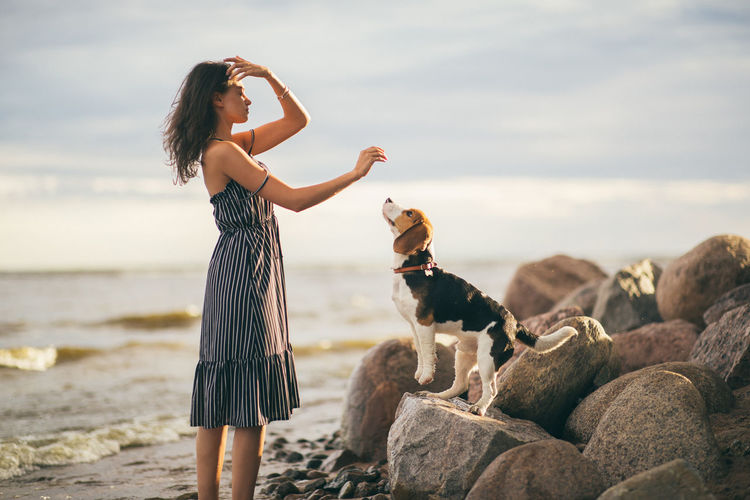 Woman with dog standing at beach