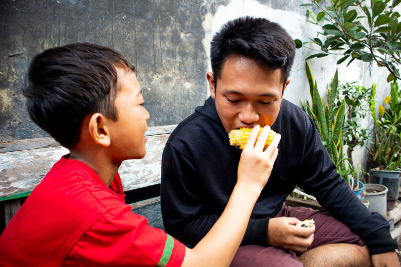 Boy feeding corn to brother