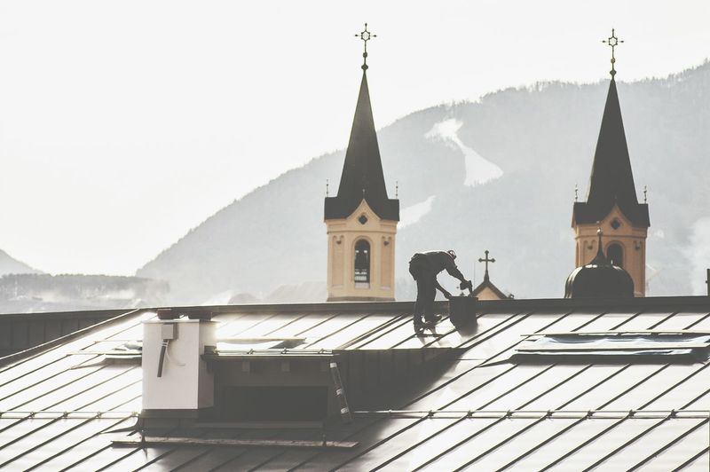 Rear view of construction worker on building roof by church