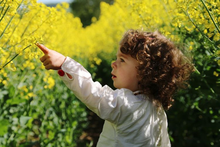 Cute girl with curly hair touching plants