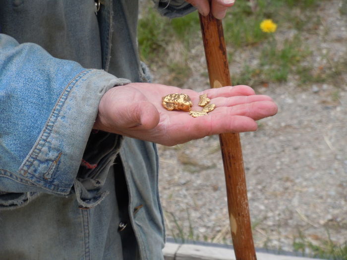 Midsection of man holding gold nugget outdoors