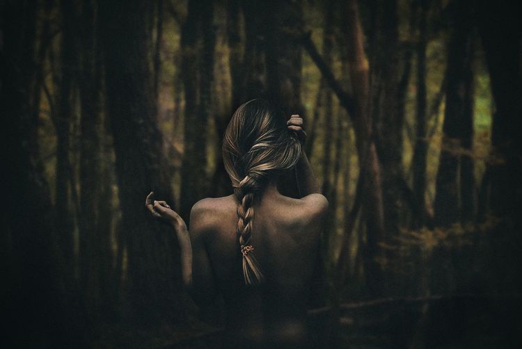 Rear view of sensual woman standing against forest