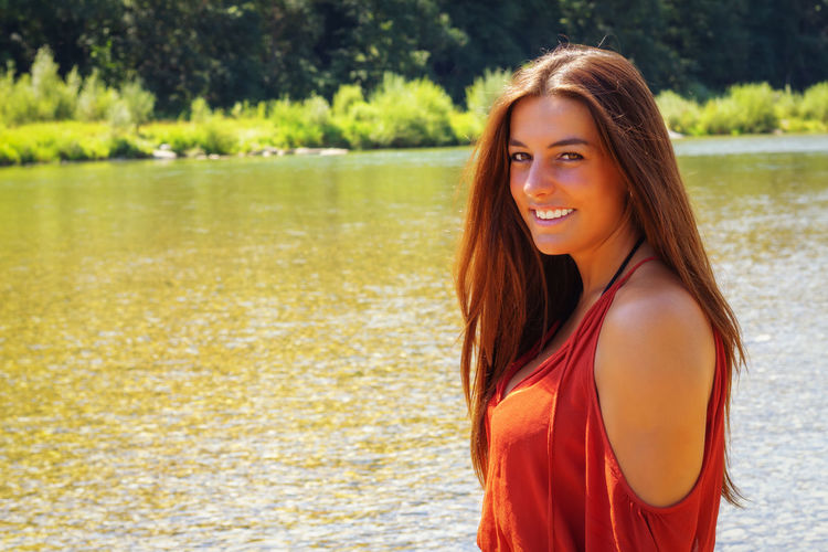 Portrait of a smiling young woman standing in lake