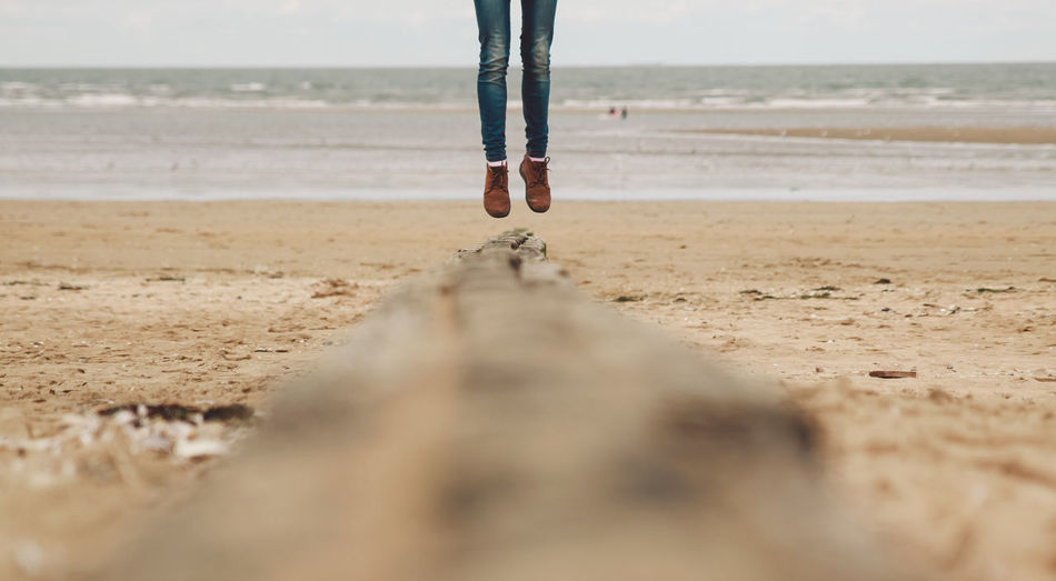 Low section of woman jumping on beach