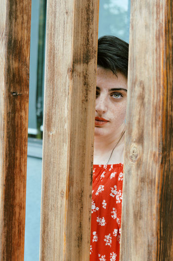 Portrait of teenage girl by wooden fence