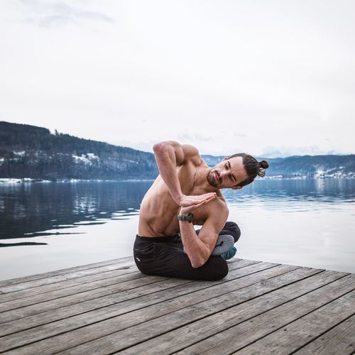 Full length of shirtless man on pier over lake