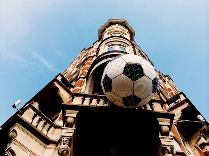 Low angle view of building with large soccer ball hanging in net