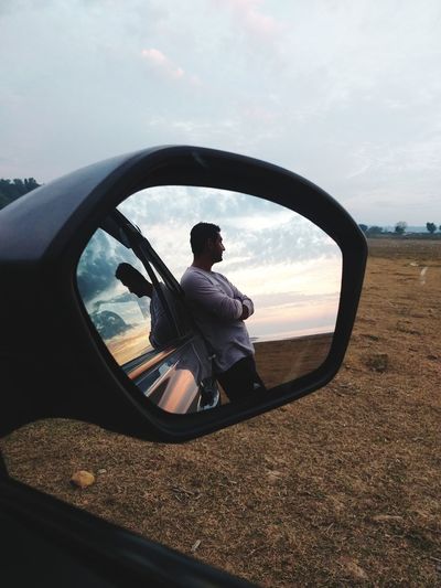 Reflection of man on side-view mirror