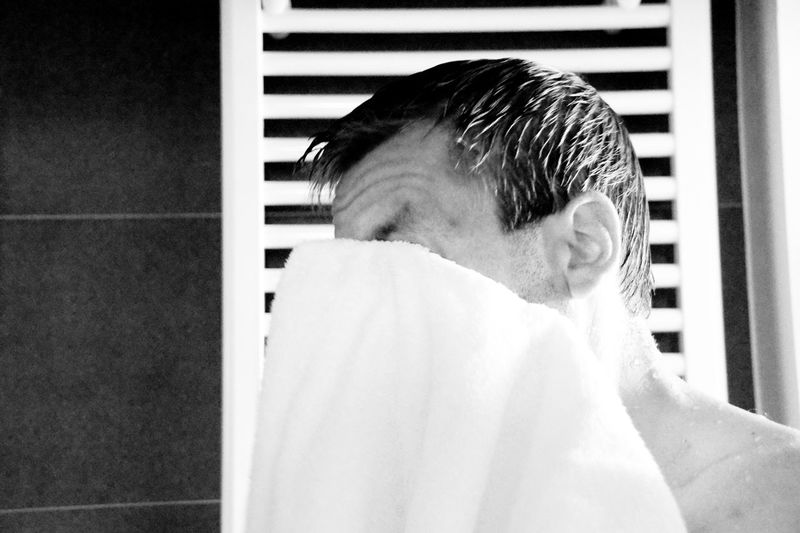 Man cleaning face with towel at home