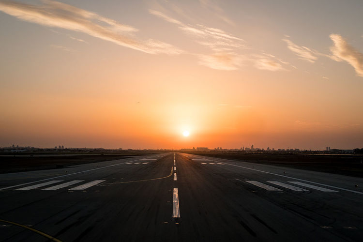 Airplane on road against sky during sunset