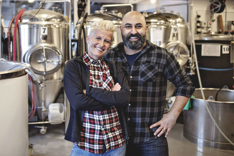 Portrait of smiling male and female partners standing in brewery