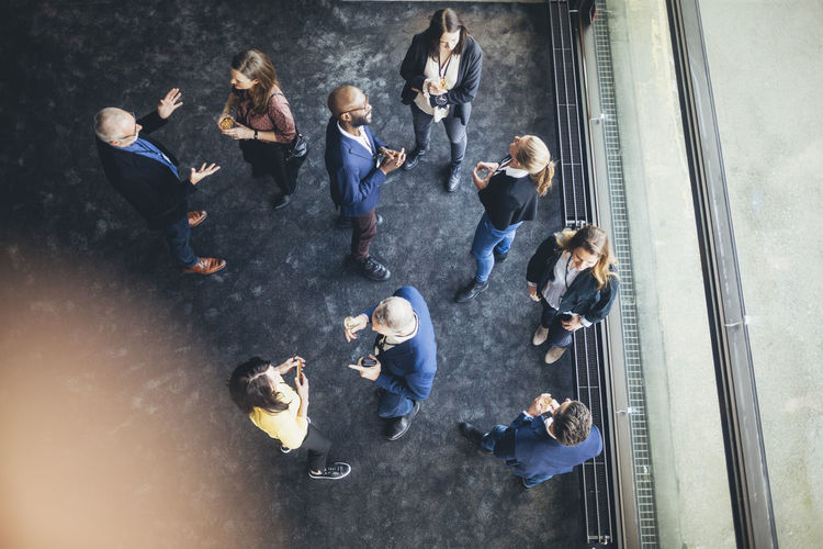 High angle view of business professionals discussing while standing at workplace