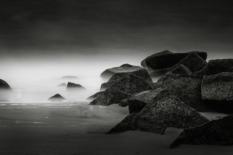Rocks at beach during foggy weather