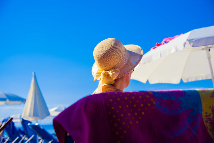 Low angle view of woman with arms raised against clear blue sky