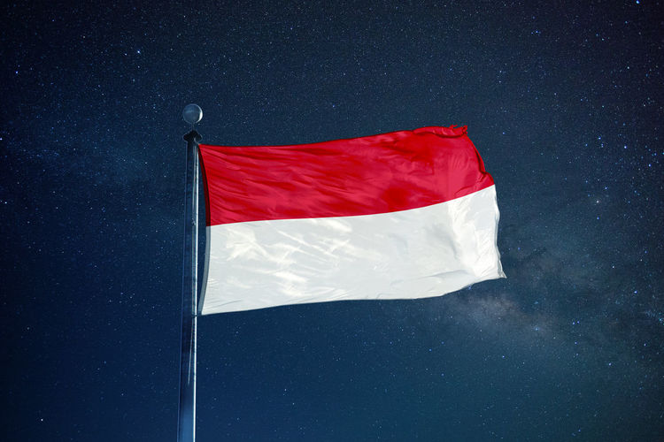 Low angle view of indonesian flag against star field sky