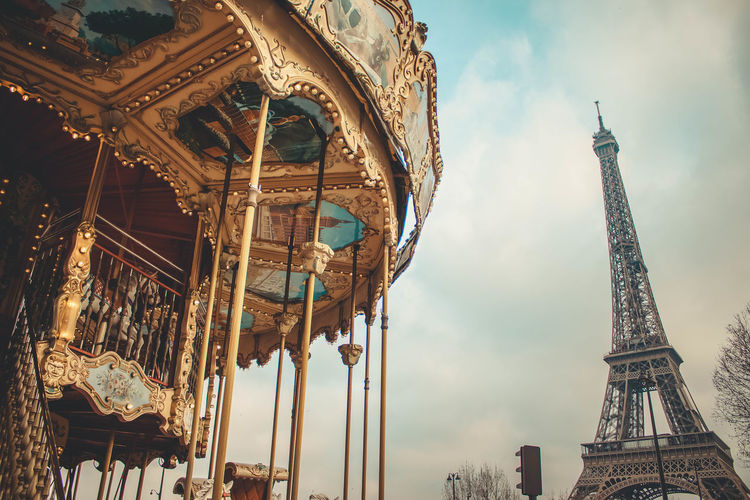 Low angle view of carousel and eiffel tower against sky