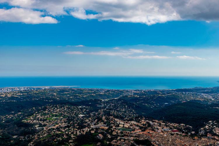 Aerial view of townscape by sea against sky
