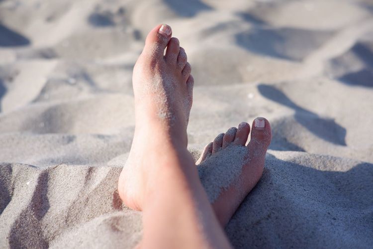 Low section of person relaxing on sand