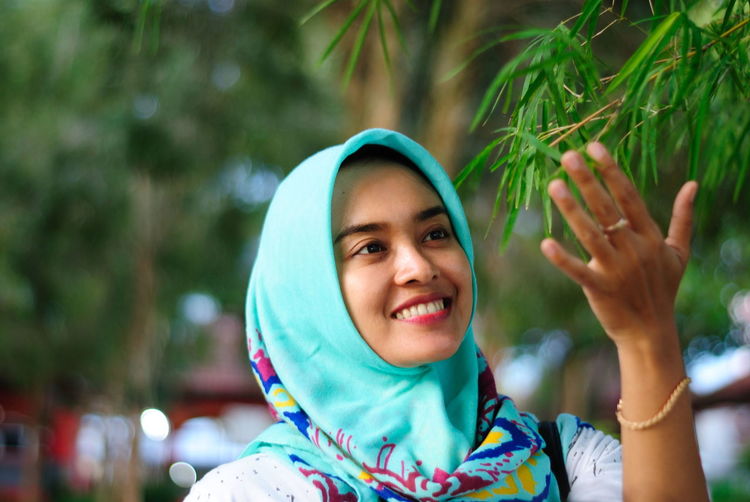 Close-up of woman wearing hijab looking at plant in park