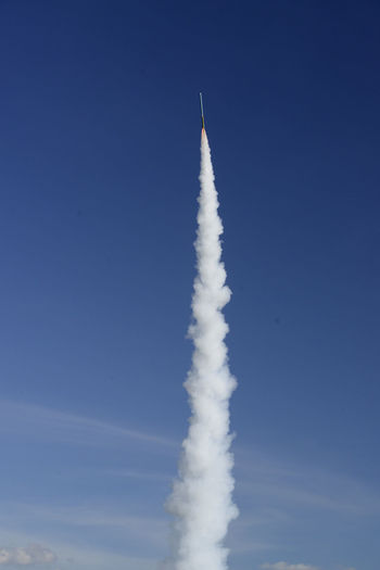 Low angle view of rocket launch against blue sky