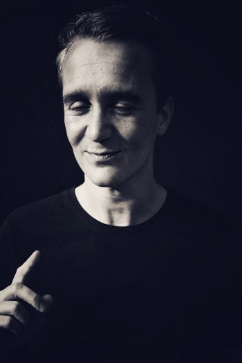 Young man holding up index finger against black background