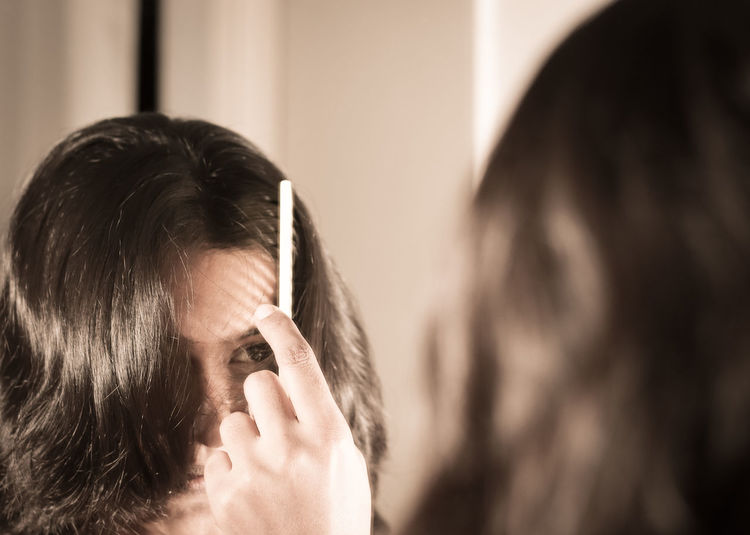 Reflection of woman combing hair on mirror