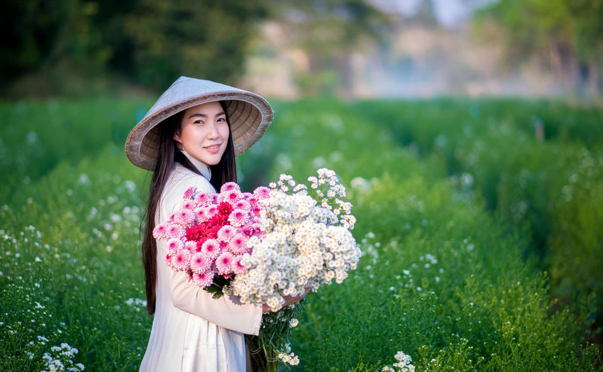Portrait of beautiful young woman with pink flower in park