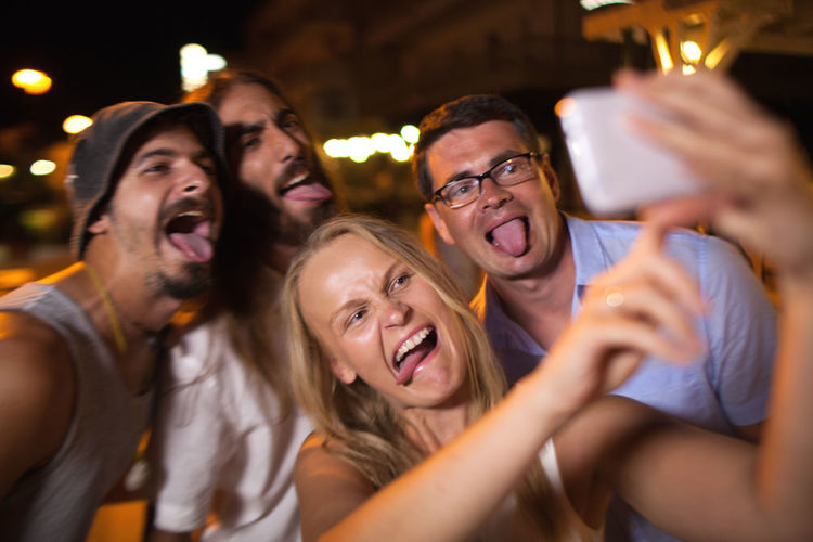 Cheerful friends taking selfie at night
