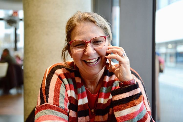 Close-up of cheerful mature woman talking on phone while sitting outdoors