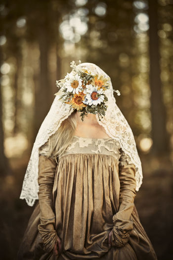MIDSECTION OF WOMAN STANDING BY FLOWER TREE