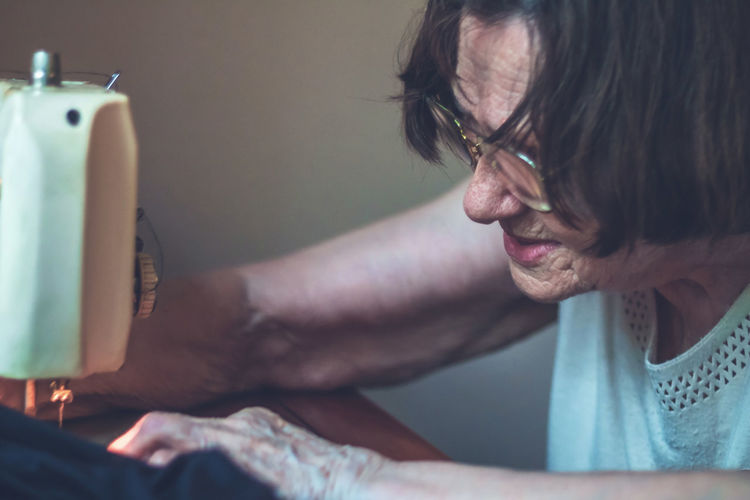 Close-up of senior woman sewing on machine