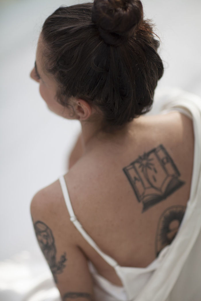 Rear view of young woman with tattoo sitting indoors