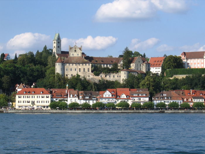 Buildings by river against sky in town