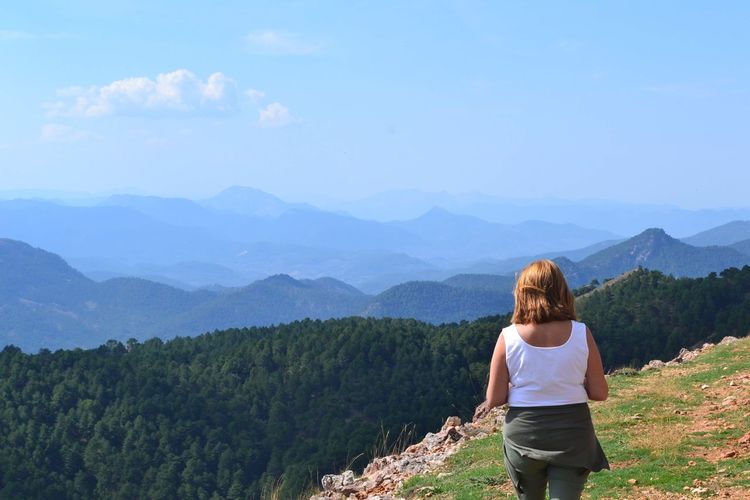 Rear view of woman standing on mountain against sky