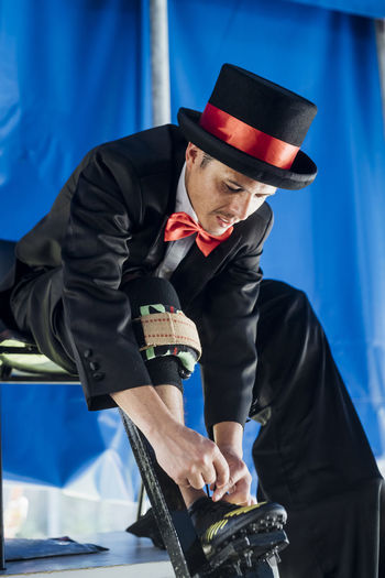 Male performer with stilts tying shoelace at tent