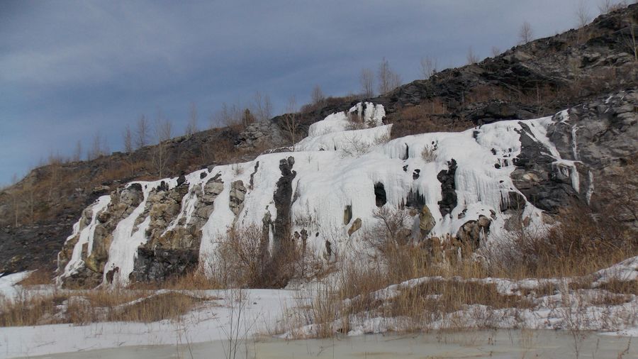 The buckthorn bushes under the icy waterfall. flooded quarry groundwater zavitinsk lithium deposits.