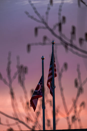 Low angle view of flags on pole against sky during sunset