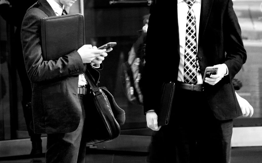 Midsection of businessmen using mobile phones