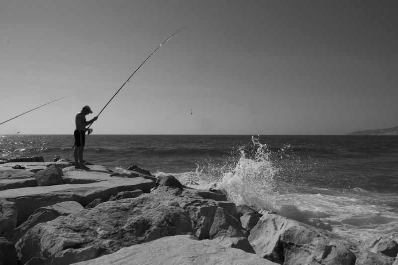 Side view of man on rock fishing in sea