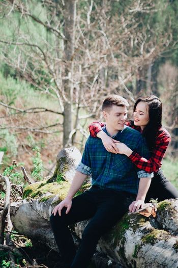 Smiling girlfriend embracing boyfriend in forest