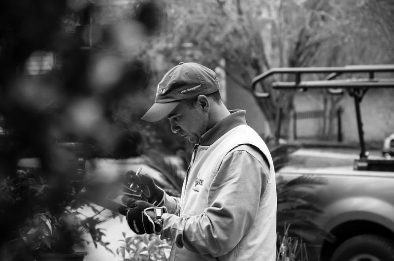 Side view of man using digital tablet by plants