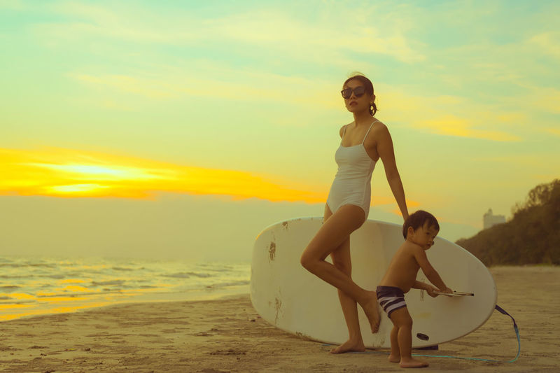 Portrait of smiling young woman on beach against sky during sunset