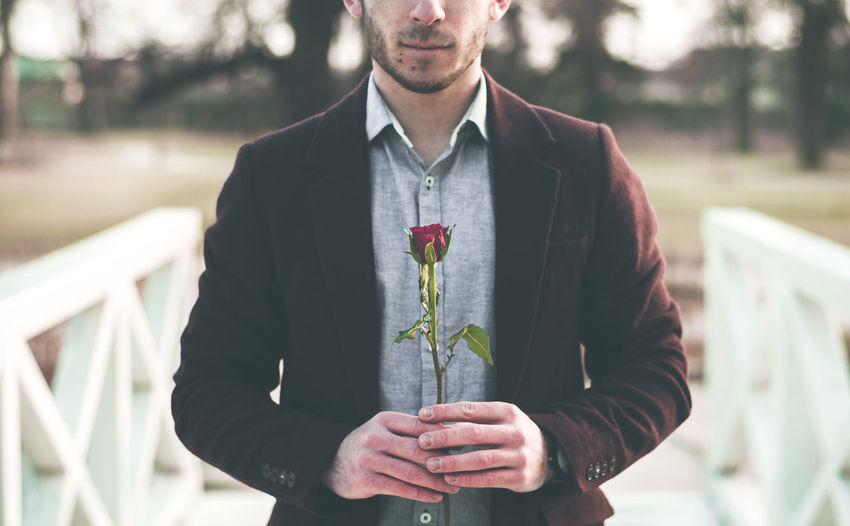 Midsection of man holding rose at park