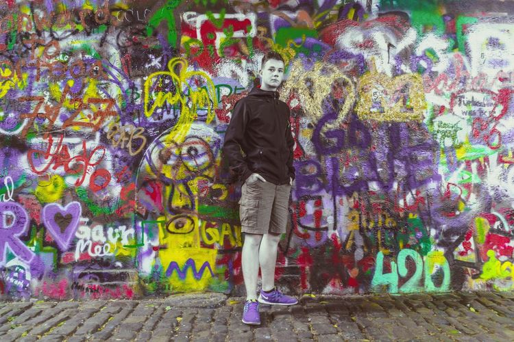 Rear view of man standing against graffiti wall