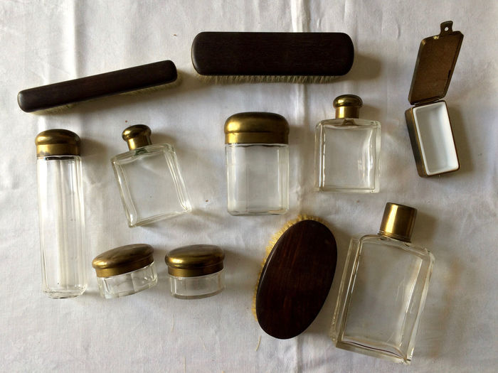 Close-up of glass perfume bottles, empty containers, and grooming brushes