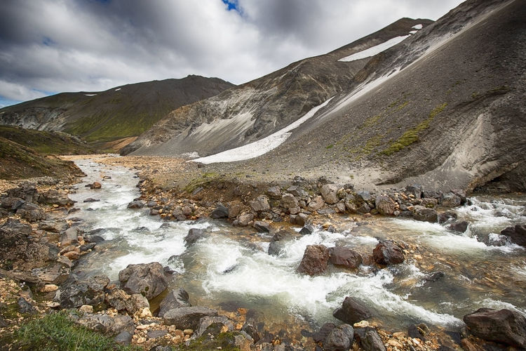 Stream flowing by mountains at landmannalaugar in winter