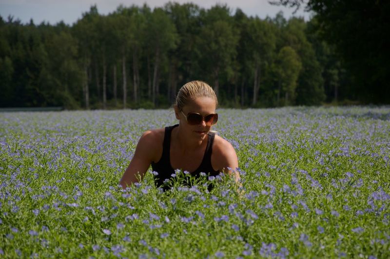 Young woman in sunglass amidst flowering field