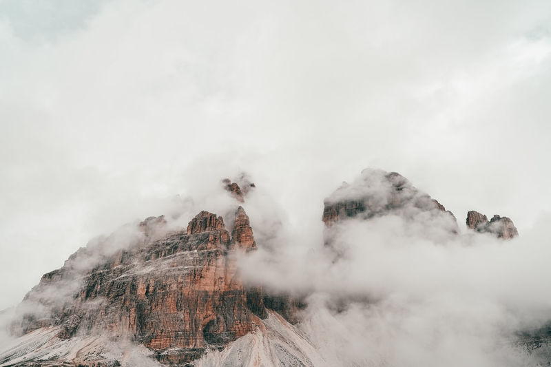 Tre cime di lavaredo mountain peaking through clouds