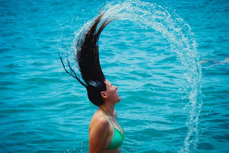 Young woman tossing hair while swimming in sea